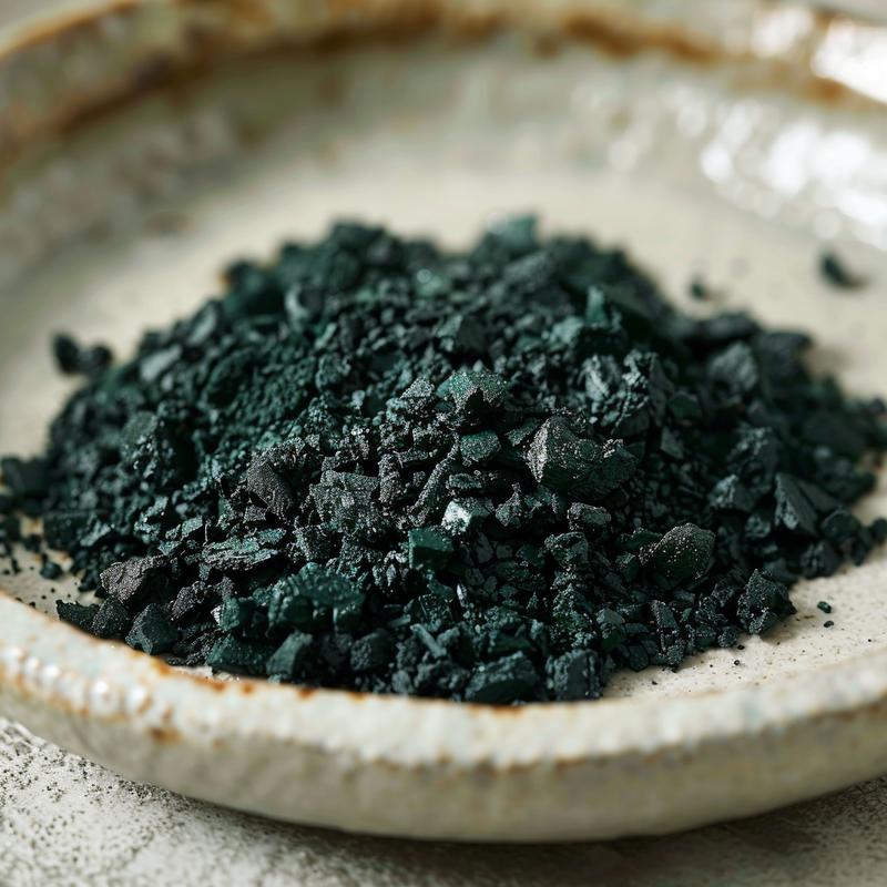 Close-up of dark green food coloring samples mixed on a light grey plate.
